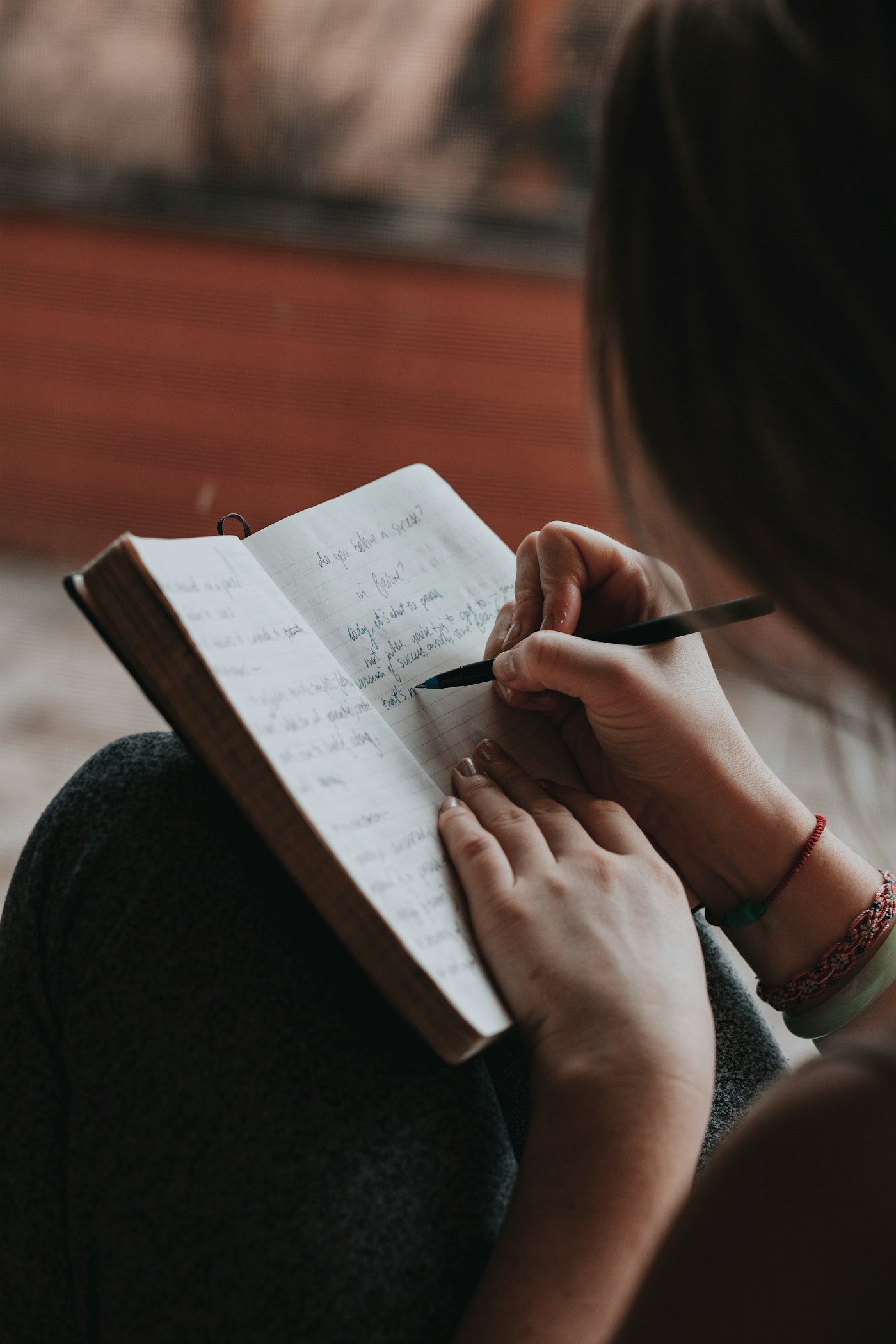 A person writing and reflecting in a notebook